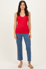 woman wearing a red ribbed tank top and blue high-waisted jeans, standing with a neutral background