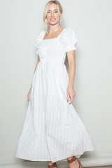 woman wearing a white puff sleeve maxi dress with a smocked bodice and tie detail