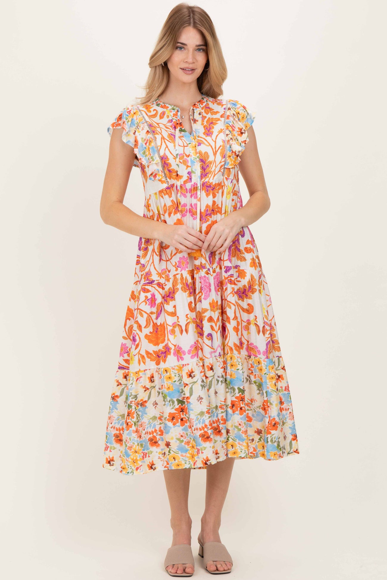 woman wearing a colorful floral midi dress with ruffled sleeves and a tiered skirt