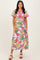 woman wearing a vibrant floral maxi dress with short, ruffled sleeves and a pink trim detail