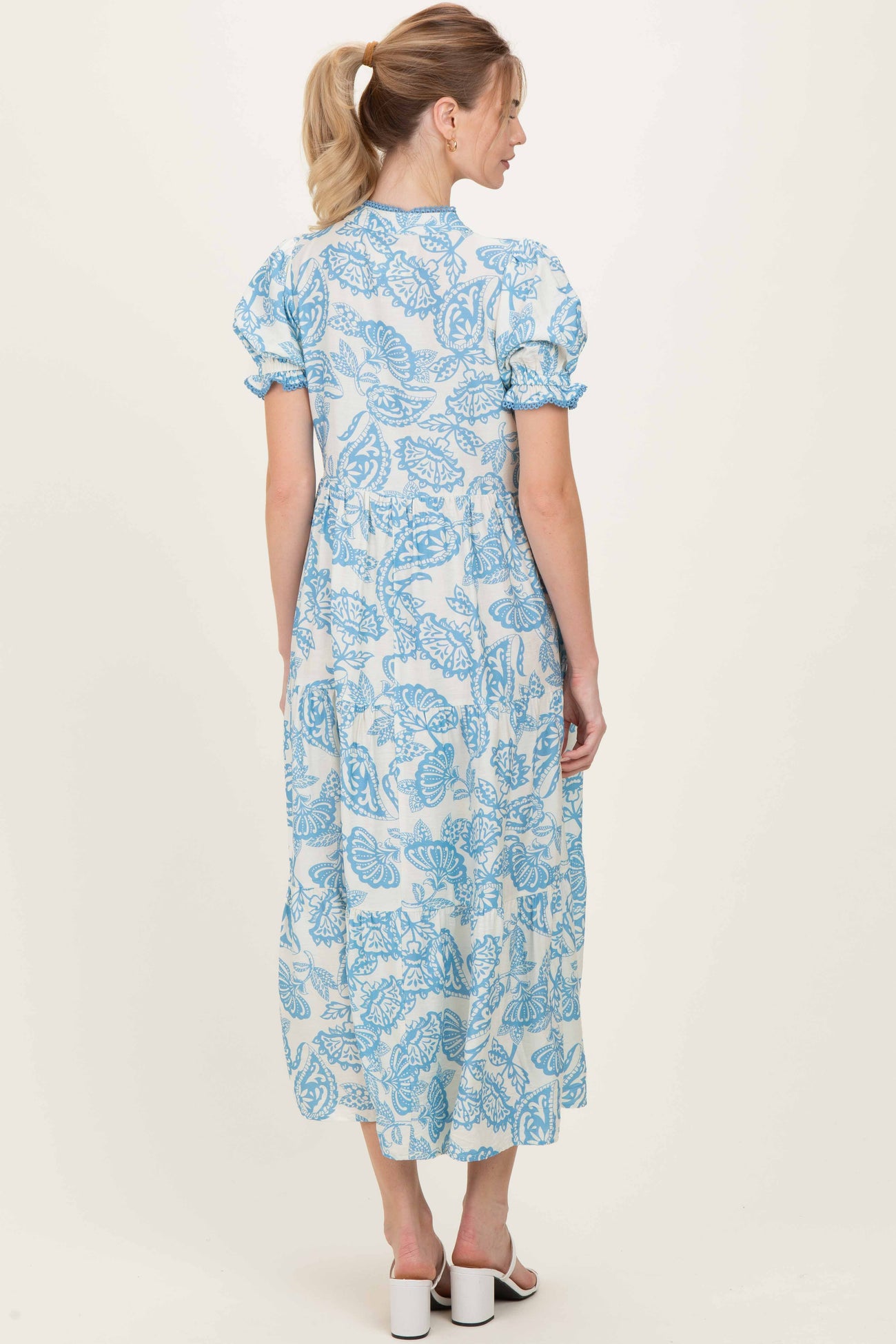 woman wearing a blue floral patterned midi dress with puff sleeves, shown from the back