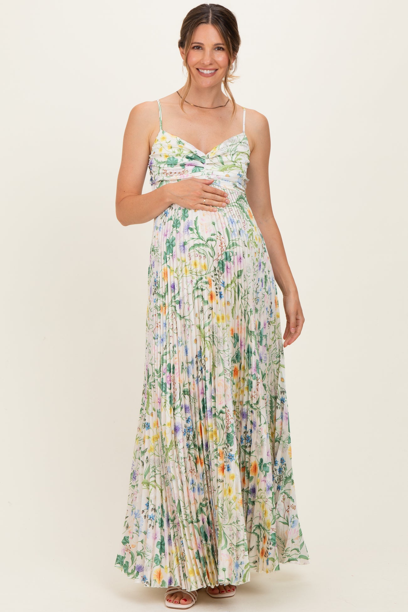 woman wearing a floral print maternity maxi dress with a fitted bodice and pleated skirt, showing her baby bump