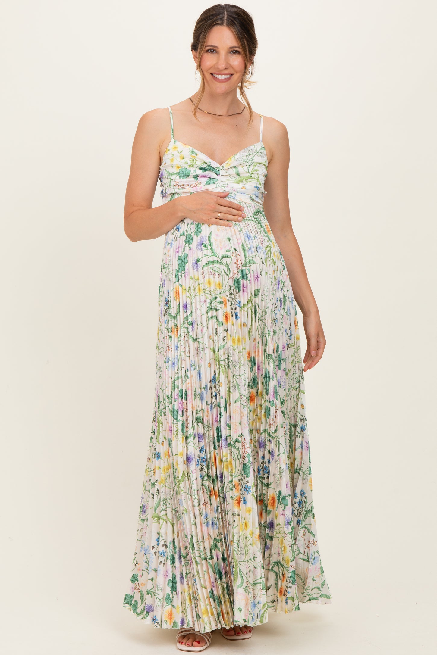 woman wearing a floral print maternity maxi dress with a fitted bodice and pleated skirt, showing her baby bump