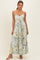woman wearing a floral maxi dress with a knotted front and spaghetti straps, standing against a light background