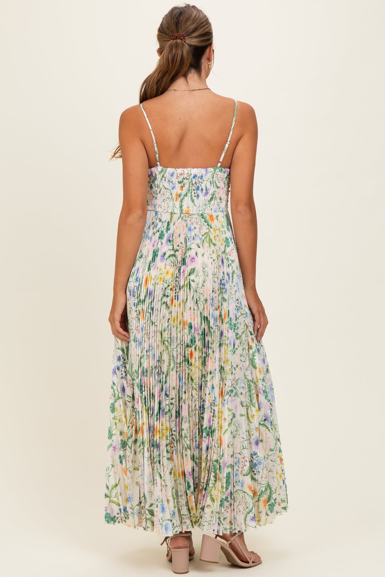 woman wearing a floral maxi dress with a smocked bodice and pleated skirt, view from the back