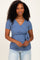 woman wearing a blue short sleeve wrap top with tie detail, styled with light blue jeans