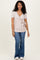 woman wearing a light pink short sleeve tie-waist top with a v-neck and flared jeans
