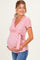 woman wearing a pink wrap maternity top with floral print and a tie detail, showcasing her baby bump