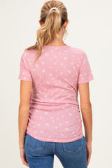 woman wearing a pink floral maternity top with a fitted style and side ruching, viewed from the back