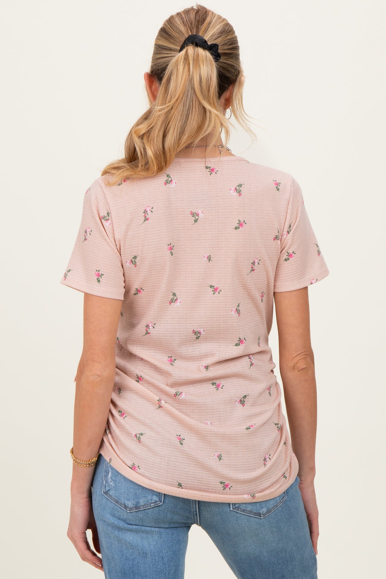 woman wearing a pink floral maternity top with gathered sides, showing a baby bump