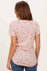 woman wearing a light pink short sleeve top with floral print and a side ruching detail, seen from the back
