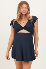 woman wearing a navy blue maternity dress with ruffle sleeves and a twist detail above the baby bump