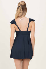 woman wearing a navy blue skater dress with ruffled straps and a fitted bodice, shown from the back