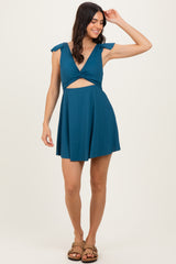 woman wearing a teal cutout dress with tie sleeves and a playful silhouette