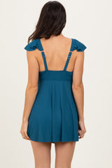 woman wearing a teal sleeveless dress with ruffled straps and a fitted bodice, seen from the back