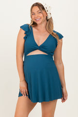 woman wearing a teal maternity dress with ruffle sleeves and a cutout detail, showing her baby bump