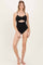 woman wearing a black ribbed one-piece swimsuit with cut-out details and button accents