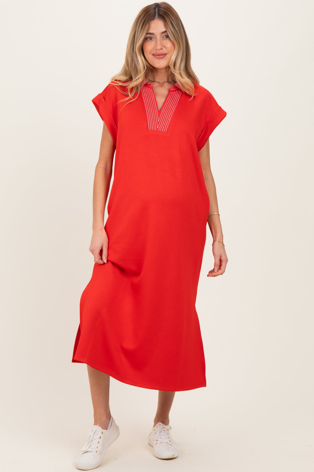 woman wearing a bright red maternity dress with a V-neck and short sleeves, standing and smiling