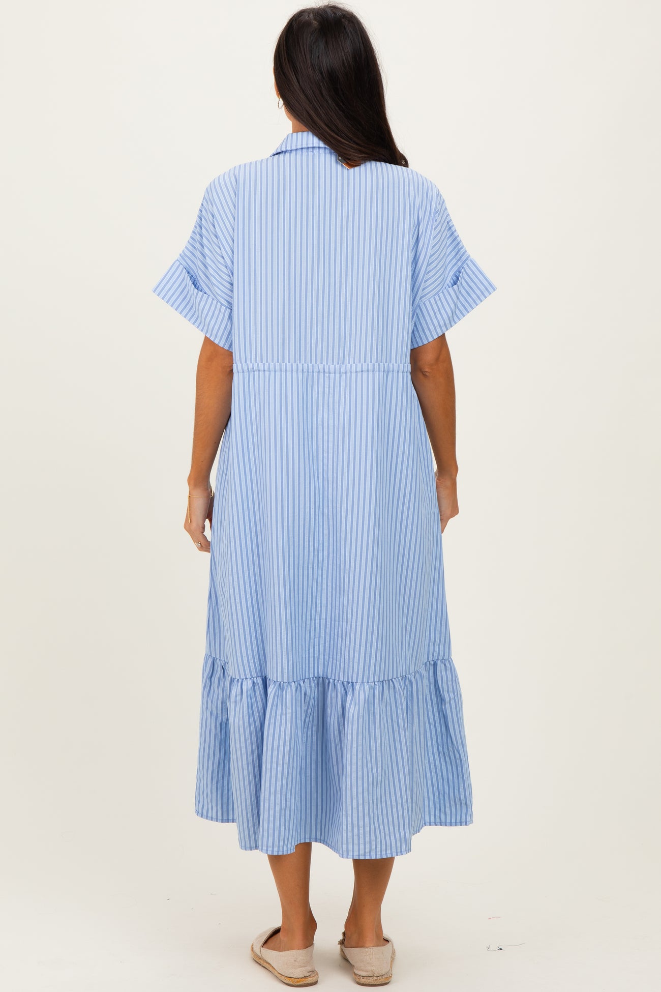 woman wearing a blue and white striped maxi dress with short sleeves and a ruffled hemline, viewed from the back