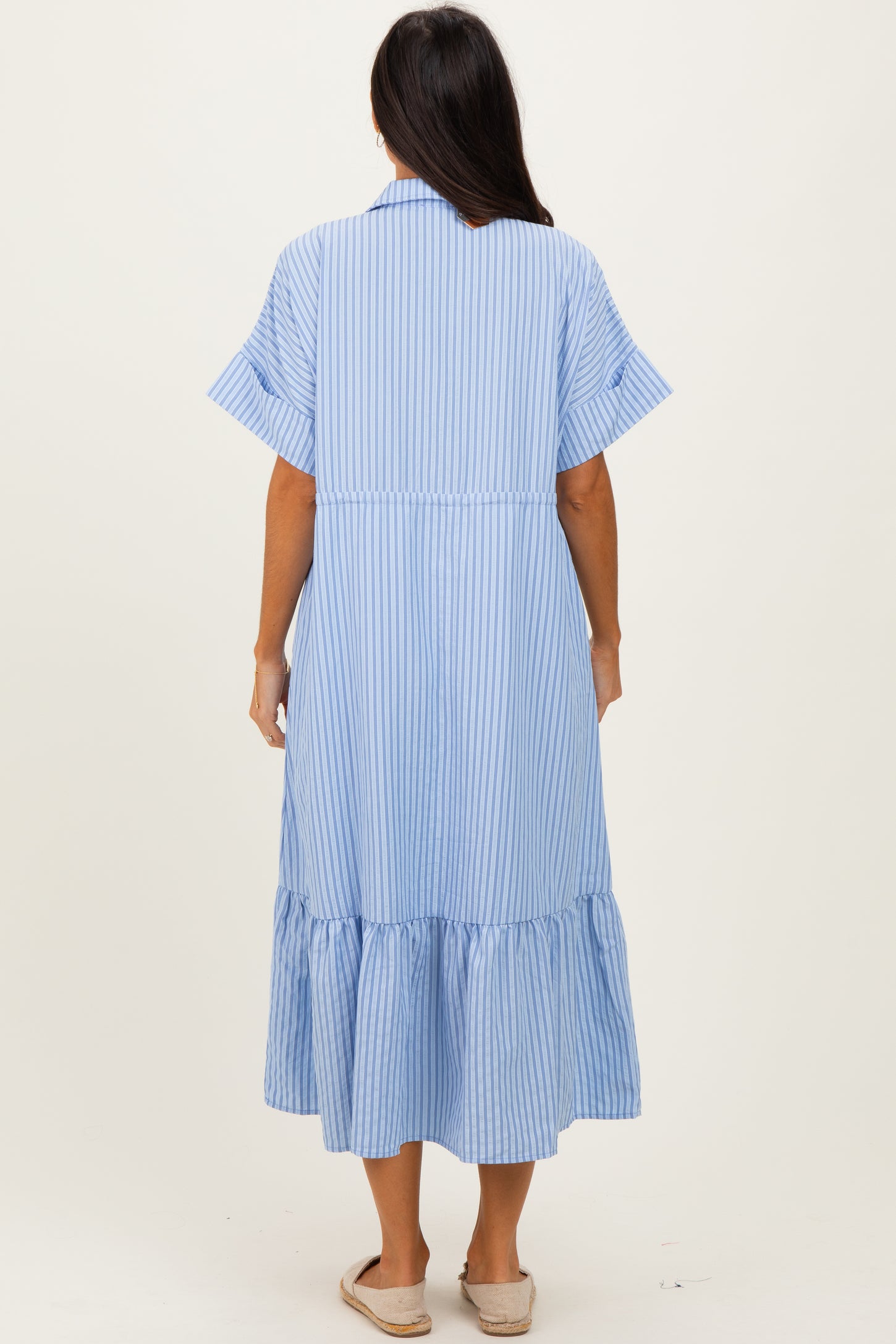 woman wearing a blue and white striped maxi dress with short sleeves and a ruffled hemline, viewed from the back