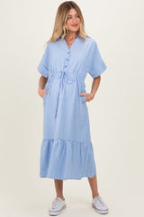 woman wearing a light blue and white striped maternity dress with tie waist and pockets, holding her baby bump