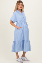 woman wearing a light blue striped maternity dress with a button-up front and ruffle hem, holding her baby bump