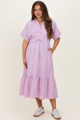 woman wearing a pink and white striped maternity dress with short sleeves and a tiered hem, holding her baby bump