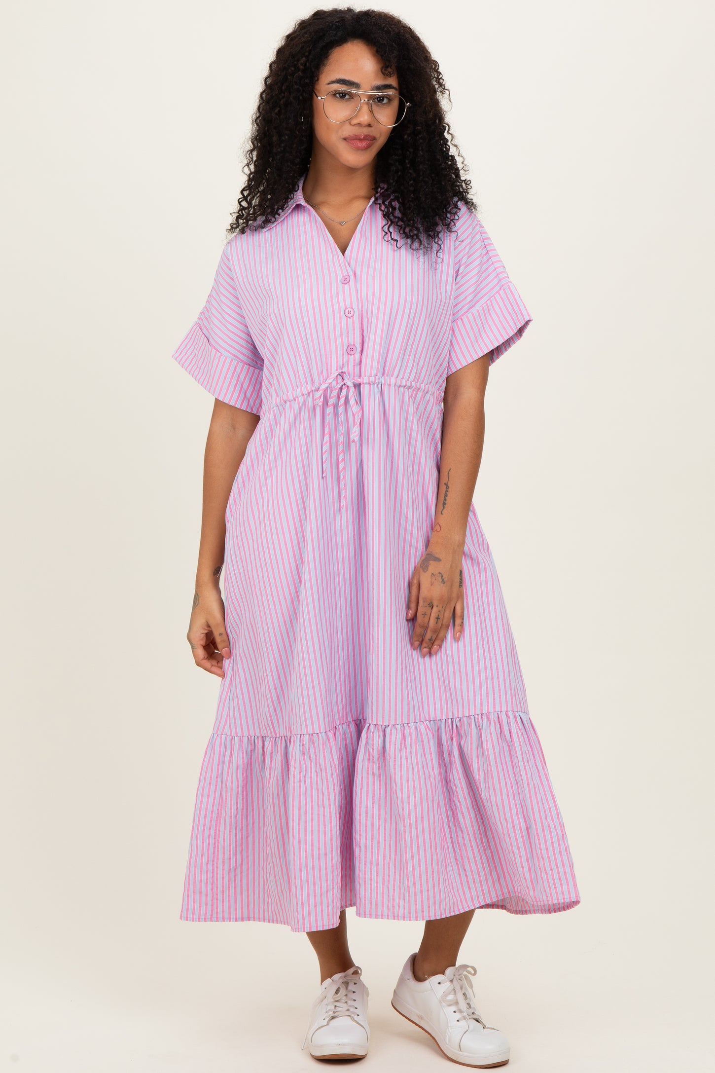 woman wearing a pink and white striped button-up midi dress with short sleeves and a drawstring waist