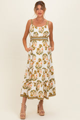 woman wearing a white floral maternity maxi dress with spaghetti straps and pockets, showing a baby bump