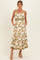 woman wearing a white floral maternity maxi dress with spaghetti straps and pockets, showing a baby bump