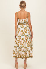 woman wearing a white floral maternity maxi dress with a green belt and adjustable straps, showing a baby bump