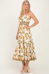woman wearing a white floral maxi dress with orange and green details, styled with a fitted waist and flared skirt