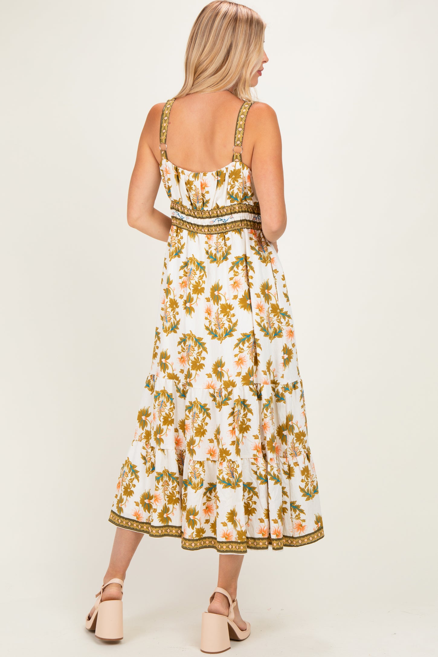 woman wearing a back view of a white floral midi dress with adjustable straps and tiered ruffles