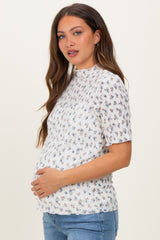 woman wearing a floral print short sleeve maternity top and holding her baby bump