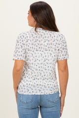 woman wearing a sheer white floral maternity top with short sleeves and relaxed fit, showing her back