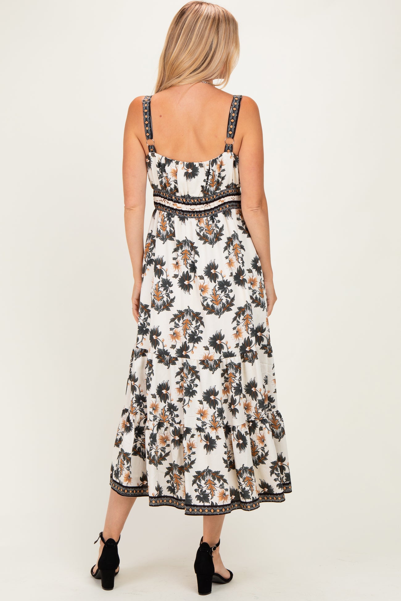 woman wearing a white floral maxi dress with adjustable straps and a tiered skirt, viewed from the back