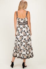woman wearing a white floral maxi dress with adjustable straps and a tiered skirt, viewed from the back