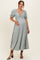 woman wearing a light green maternity dress with puff sleeves and a pleated design, cradling her baby bump