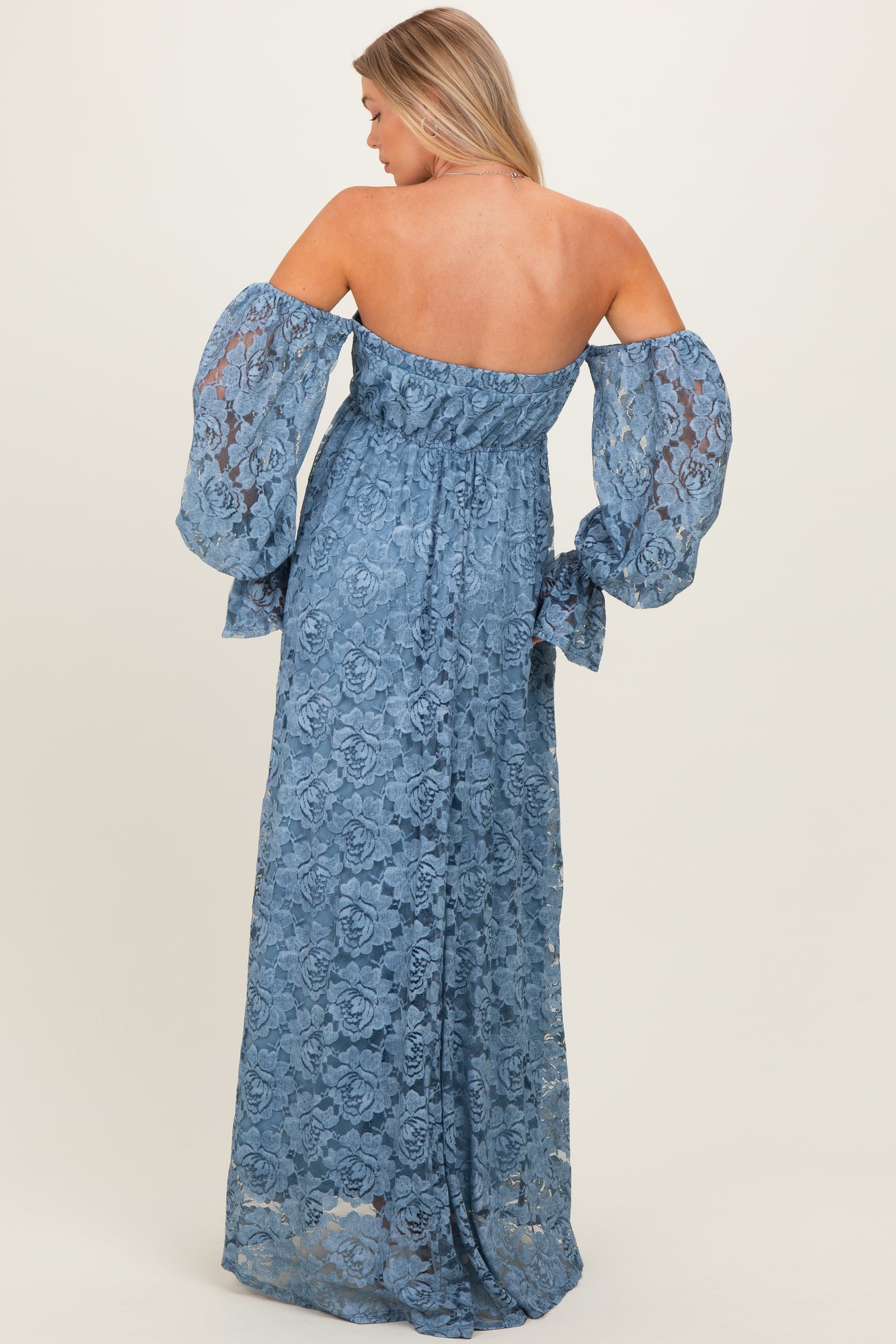 woman wearing a blue lace off-the-shoulder maternity maxi dress with bell sleeves, showing the back view