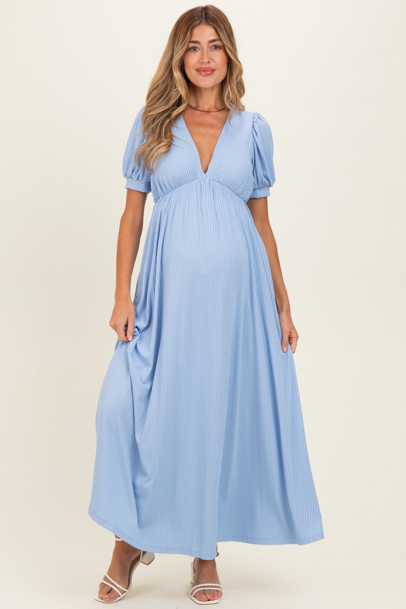 woman wearing a light blue maxi dress with puff sleeves and a deep v-neck, showing her baby bump