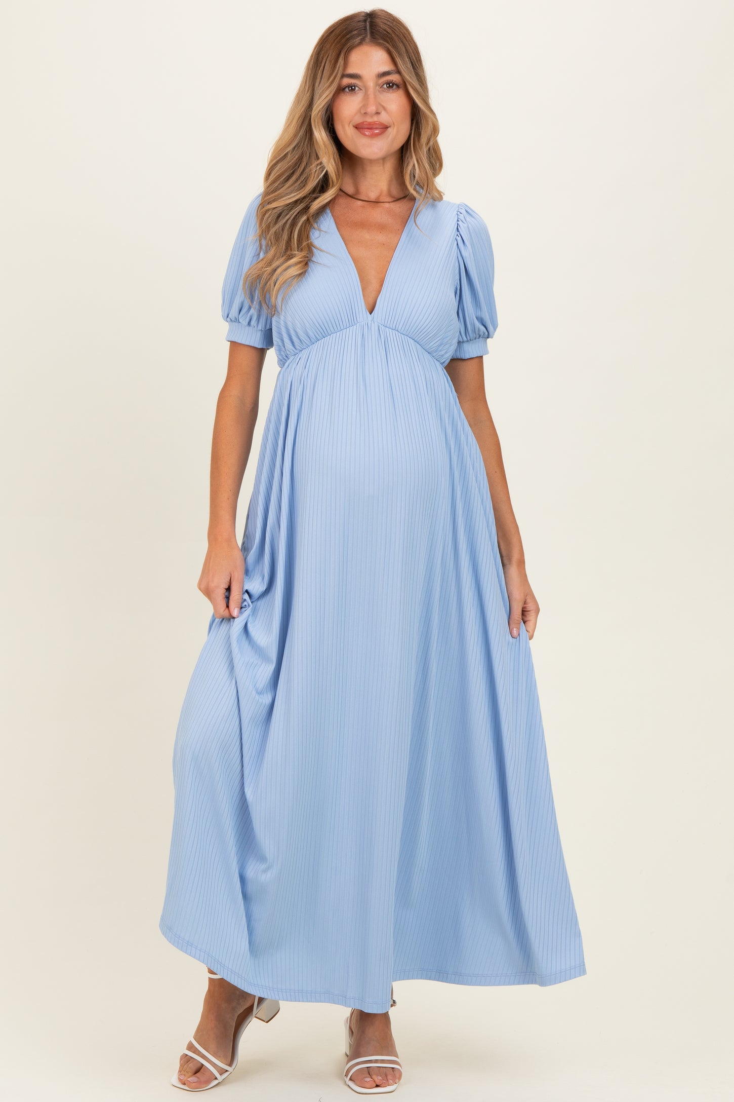 woman wearing a light blue maxi dress with puff sleeves and a deep v-neck, showing her baby bump