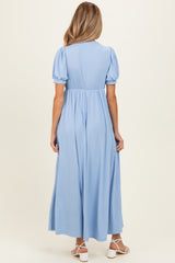 woman wearing a light blue maternity dress with short puff sleeves and a flowing maxi length, showing her baby bump