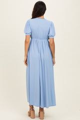 woman wearing a light blue pleated maxi dress with short puff sleeves and a fitted waist from the back