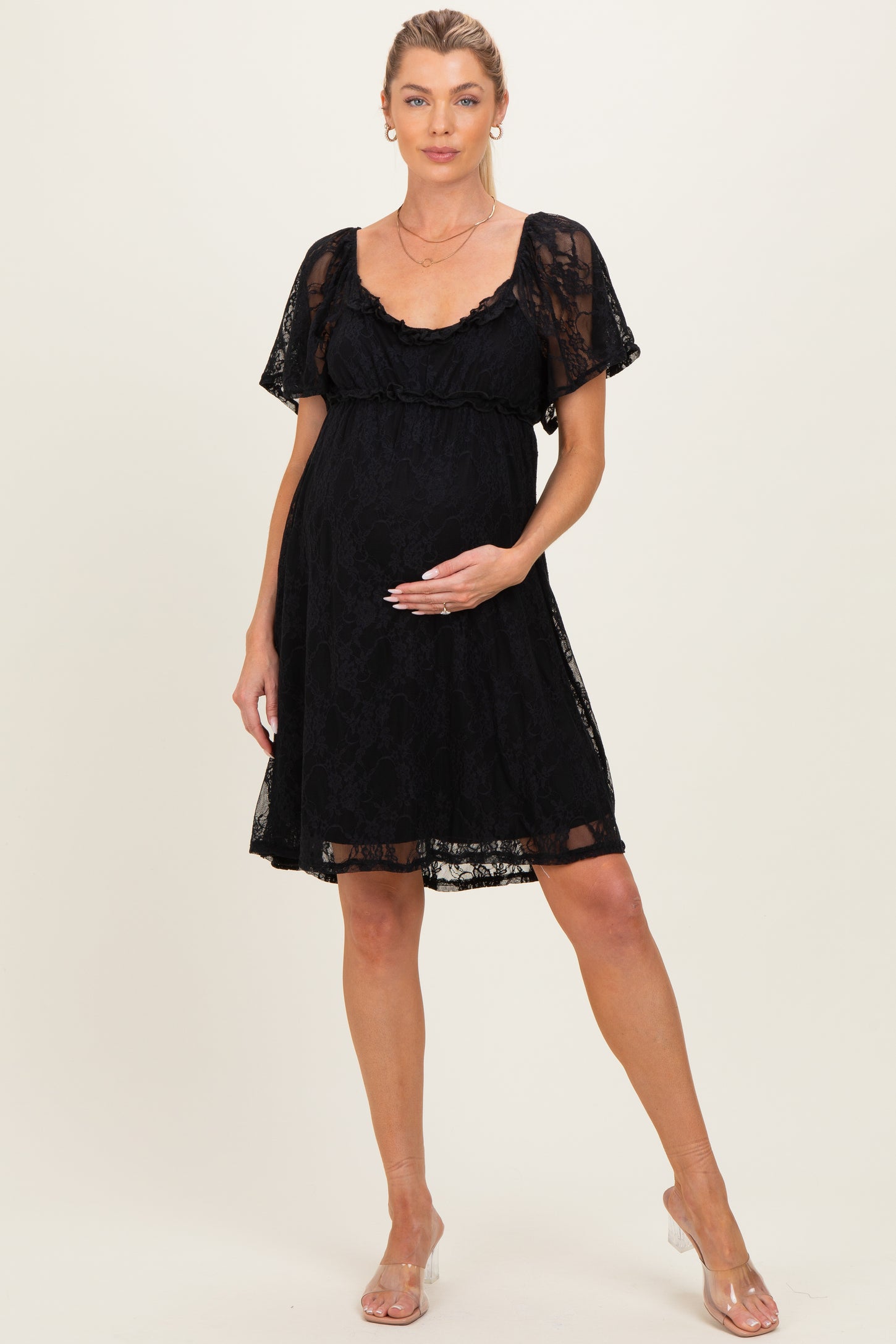woman wearing a black lace maternity dress with short sleeves and a fitted empire waist, holding her baby bump