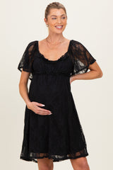 woman wearing a black lace maternity dress with short flutter sleeves and holding her baby bump