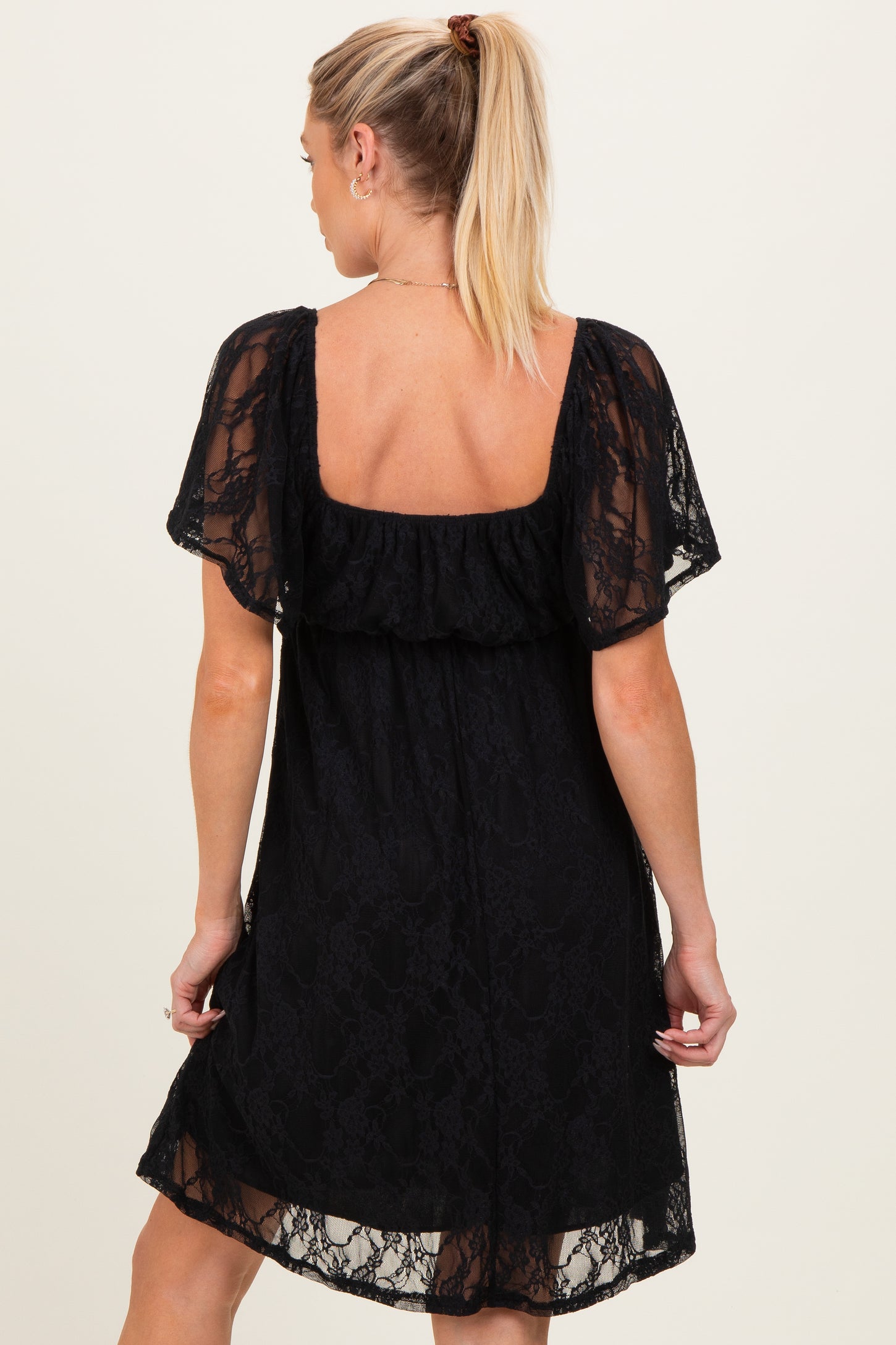 woman wearing a black lace maternity dress with short sleeves and a relaxed fit, showing her back