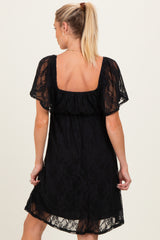 woman wearing a black lace maternity dress with short sleeves and a relaxed fit, showing her back