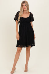 woman wearing a black lace short dress with a square neckline and short sleeves, styled casually