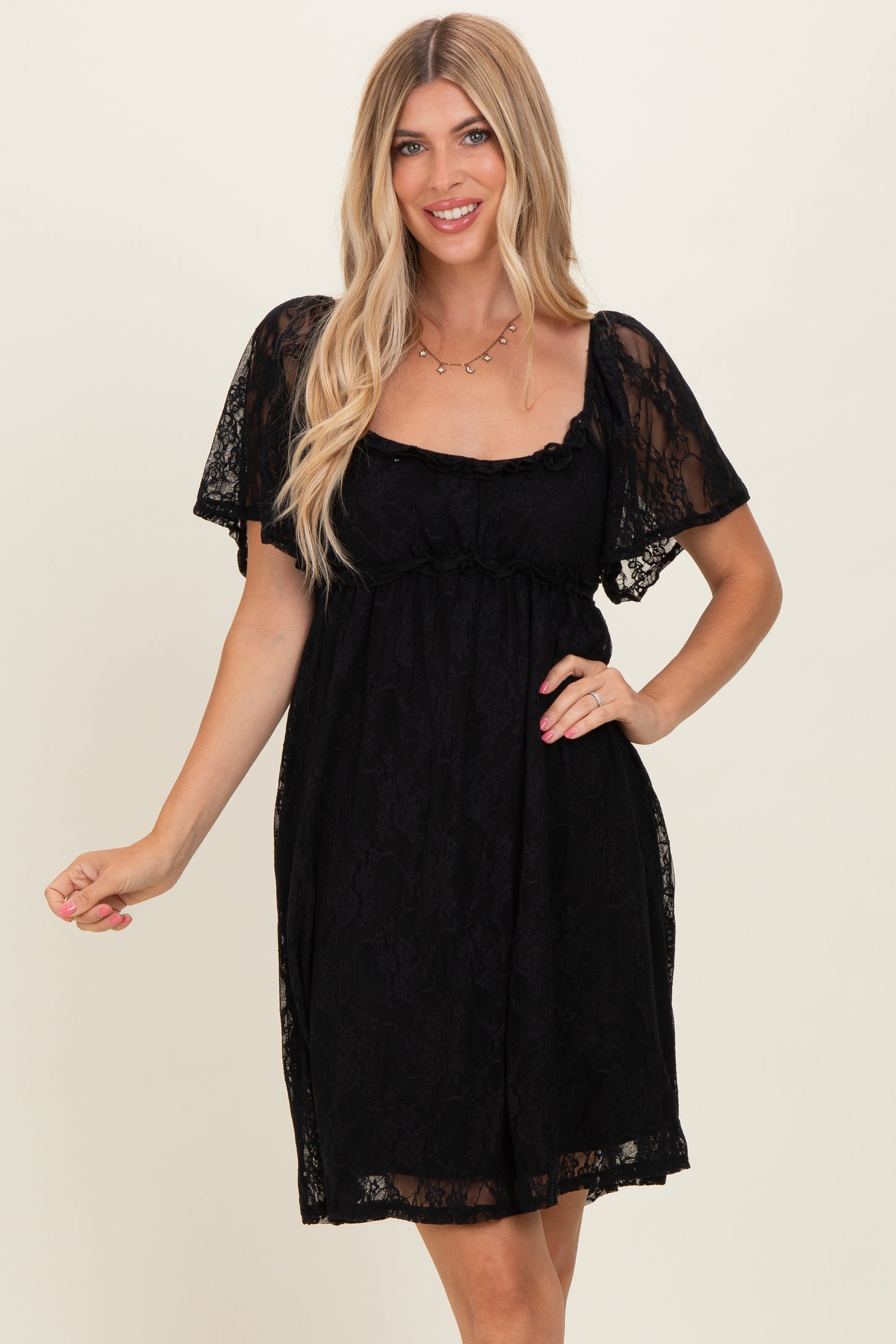 woman wearing a black lace short sleeve dress with a square neckline and flowy silhouette
