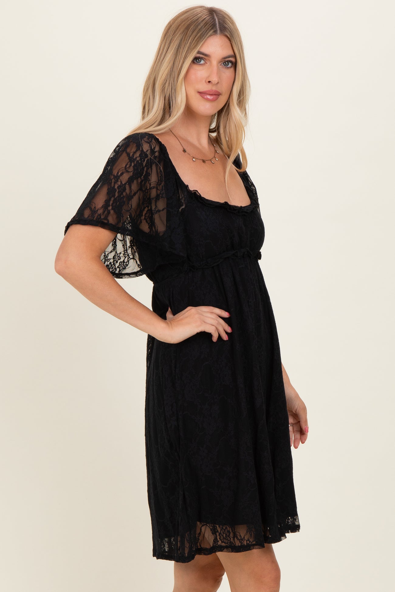 woman wearing a black lace short sleeve dress with a cinched waist and a flowy silhouette
